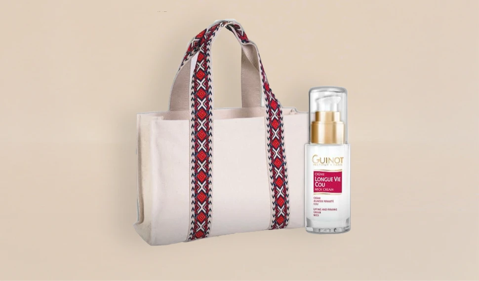 Eine Weekender Bag und das Guinot Produkt Longue Vie Cou stehen vor einem beigen Hintergrund.