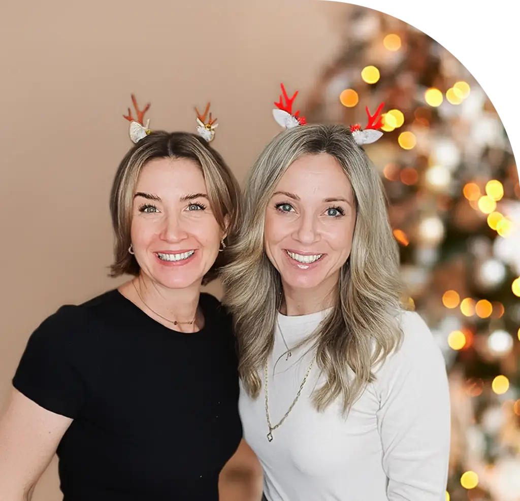 Jasmin Haberl und Julia Schmid schauen freundlich in die Kamera. Hinter ihnen steht ein leuchtender Weihnachtsbaum.